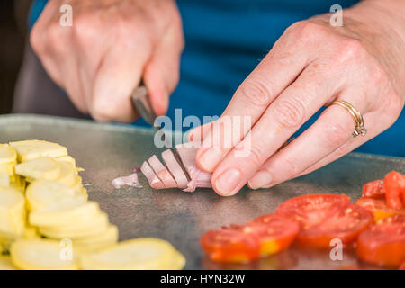 After removing the paper outer covering of the shallot, place it on a cutting board and using a thin utility knife, cut thin slices to use as a pizza  Stock Photo