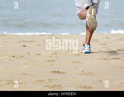 Low angle rear view of young man jogging at the beach Stock Photo