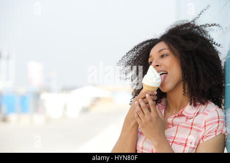 Close up portrait of a young woman licking ice cream outdoors in summer Stock Photo
