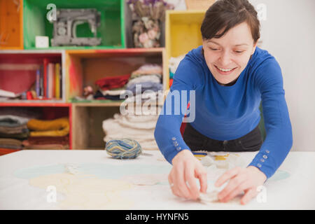 Young woman tailoring in her own small business crafting atelier. Stock Photo
