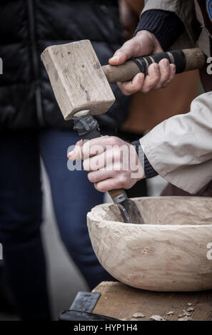 Man's hands of the joiner do a bowl, beats a hammer on a chisel Stock Photo