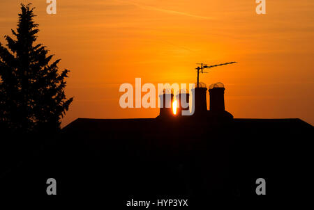 Wimbledon, London, UK. 6th April 2017. Brilliant orange sunset between rooftop chimneys in SW London after a beautiful spring day in the capital. Credit: Malcolm Park editorial/Alamy Live News. Stock Photo