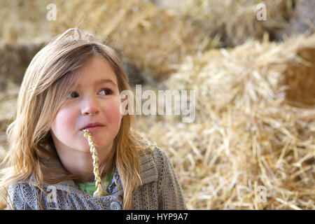 Close up portrait of a young girl relaxing at farm with straw in mouth Stock Photo