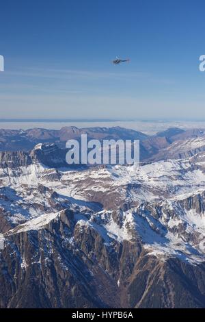Rescue helicopter next to Mont Blanc and surrounding peaks in the French Alps above the village of Chamonix Stock Photo