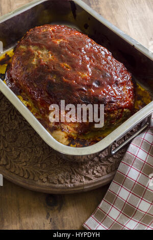 Classic American meatloaf made with ground beef oatmeal onions and a ketchup brown sugar and mustard glaze in a steel roasting pan hot out of the oven Stock Photo