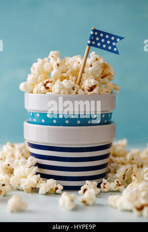 Homemade buttered popcorn served in colorful bowls decorated with party flags. Popcorn arranged in striped and spotted bowls. Stock Photo