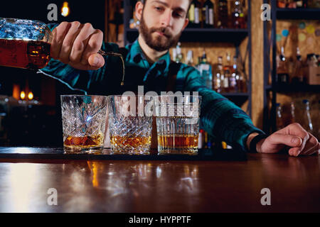 The barman pours alcohol into a glass. Close-up Stock Photo