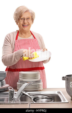 Cheerful elderly woman wiping plates and looking at the camera isolated on white background Stock Photo