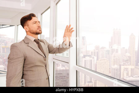 Smart advancements. Serious businessman using transparent screen and standing near window while working in the office Stock Photo