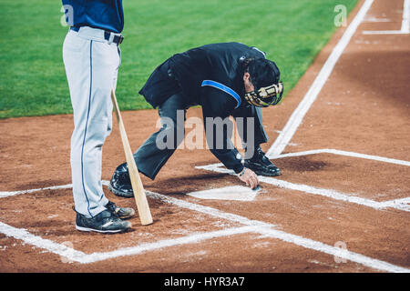 Baseball umpire cleaning home plate Stock Photo