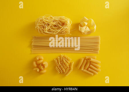 Assorted types of pasta on yellow background. Various forms of pasta. Stock Photo