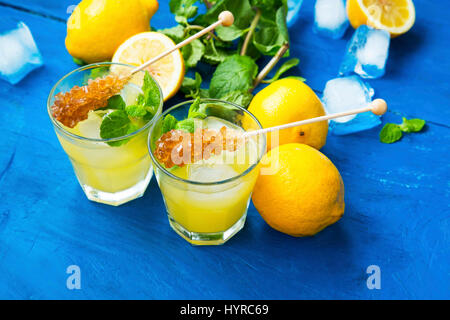 Fresh lemonade glasses with sugar sticks, lemons, mint herb and ice cubes Stock Photo