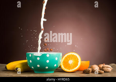 Healthy home made breakfast of Falling muesli and milk, apples, fresh fruits, walnuts. Served with fresh, sliced oranges. Stock Photo