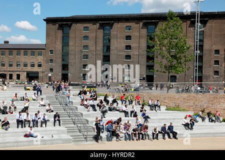 Students and office workers enjoying the sun in Granary Square by Regent’s Canal, King’s Cross, London Stock Photo