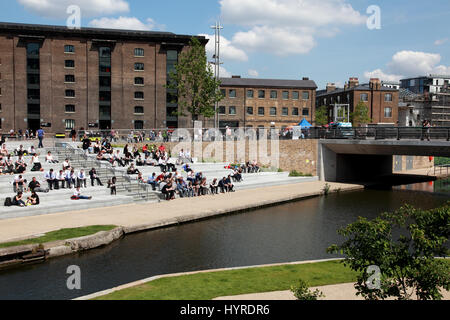 Students from Central St. Martins art school, UAL, enjoying the sun in Granary Square by Regent’s Canal, King’s Cross, London Stock Photo