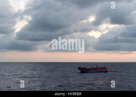 A 17 meter long wooden boat, found in the morning around 15 nautical miles away from the Libyan coast. 399 people, who are on board are trying to cros Stock Photo