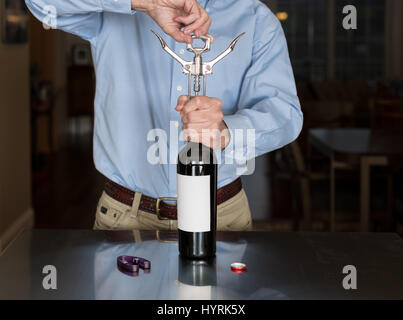 Senior man opening wine bottle with blank label Stock Photo