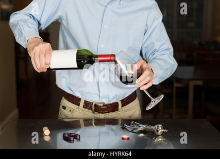 Senior man pouring from wine bottle with blank label Stock Photo