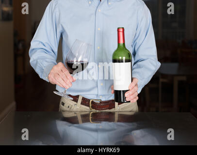 Senior man pouring from wine bottle with blank label Stock Photo