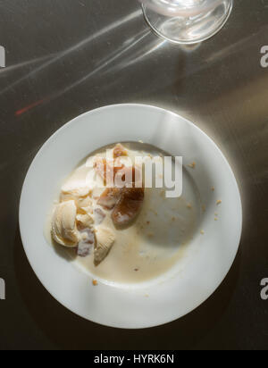 Wine glass leaves shadow across finished dinner plate Stock Photo