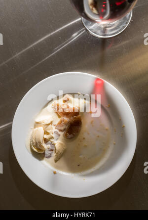 Wine glass leaves shadow across finished dinner plate Stock Photo
