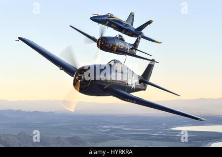 A U.S. Navy Blue Angels F/A-18 Hornet fighter aircraft (middle) flies alongside a USN F6F Hellcat World War II-era fighter aircraft (front) and a F8F Bearcat World War II-era fighter aircraft (back) during a heritage flight over the Salton Sea March 9, 2017 near Mecca, California. The Hellcat and Bearcat aircraft models were used by the Blue Angels shortly after the teams inception in 1946. Stock Photo