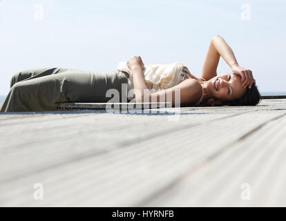 Portrait of a cheerful young woman lying down enjoying a summer day Stock Photo