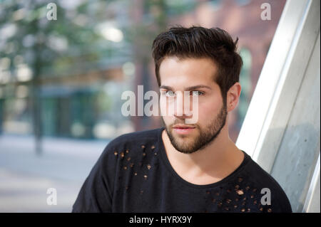 Close up portrait handsome young man with beard posing outdoors Stock Photo