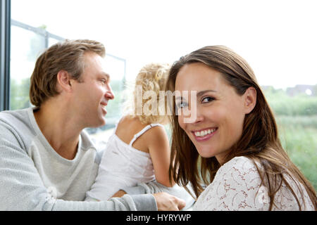 Close up portrait of smiling mother with father and baby looking out window Stock Photo