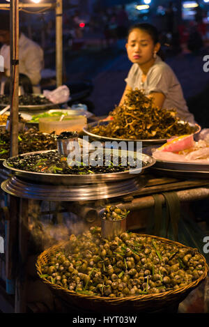 Vertical close up view of snails, water beetles, frogs and crickets for sale at a street food market in Siem Reap, Cambodia. Stock Photo