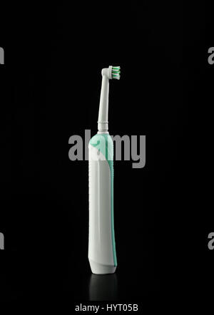 Modern electric toothbrush with used head vertical on a black background Stock Photo