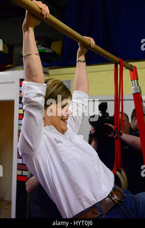 SNP leader and First Minister Nicola Sturgeon tries out on the high bar on a campaign visit to a children's gymnastic club in Cumbernauld Stock Photo