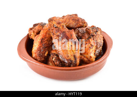 closeup of some barbecue chicken wings in an earthenware plate on a white background Stock Photo