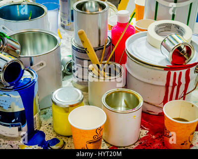 Paintbrushes dripping paint of various colors into containers, paint cans and colored brushes on the white background Stock Photo