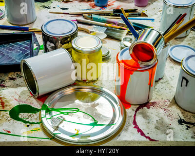 Paintbrushes dripping paint of various colors into containers, paint cans and colored brushes on the white background Stock Photo