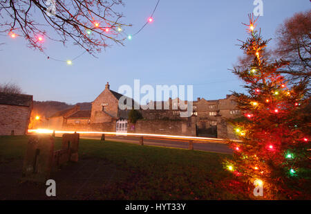 Christmas decorations by the wooden stocks on the  village green in Eyam, Peak District National Park, England UK Stock Photo
