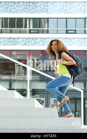 Portrait of a female student walking up stairs to college Stock Photo