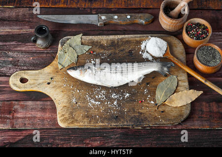 Fresh smelt fish with salt and pepper on the kitchen cutting board, view from the top Stock Photo