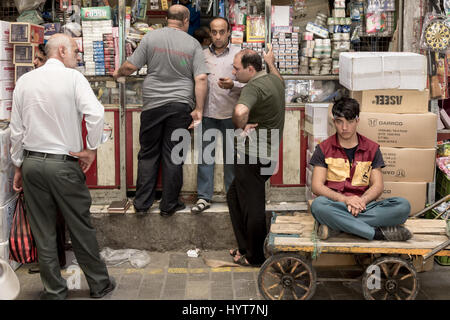 TEHRAN, IRAN - AUGUST 14, 2016: Merchants and delivery boys having a break and discussing in a covered street of Tehran bazaar   Old and young iranian Stock Photo