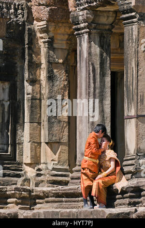 Vertical portrait of newly weds in traditional Cambodian dress being affectionate at Angkor Wat in Cambodia Stock Photo
