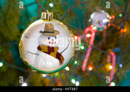 A bsnowman reflected in a Christmas tree ornament with candy canes and lights on a Christmas tree. Stock Photo