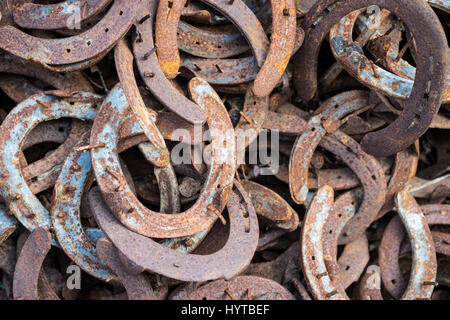 Heap of used and worn rusty Horseshoes outside blacksmith farriers shop or smithy Stock Photo