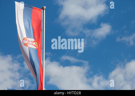 Photo of the official flag of the republic of Serbia, with a backround of blue sky and clouds  Picture of the Serbian flag taken in from of a sunny ba Stock Photo