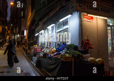 ISTANBUL, TURKEY - DECEMBER 28, 2015: Food shop on a typical street of Galata in the evening, a veiled woman passing by  Picture of a typical food sto Stock Photo