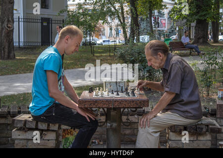 KIEV, UKRAINE - AUGUST 17, 2015: Old and young men playing chess in Taras Shevchenko Park, kiev, capital city of Ukraine  Picture of a chess clock wit Stock Photo