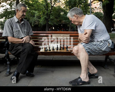 LVIV, UKRAINE - AUGUST 19, 2015: Old men playing chess on a bench in a park of Lviv  Picture of chess players, elder people  in one of the public park Stock Photo