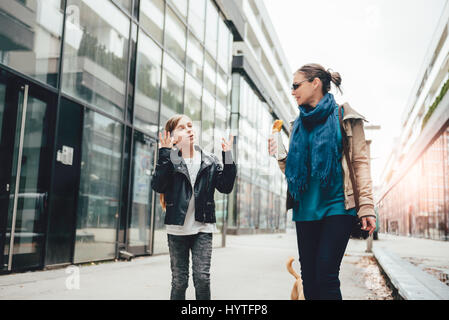 Mother and daughter walking down the city streets and eating sandwich Stock Photo