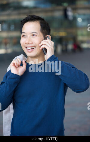 Close up portrait of a smiling asian man calling with mobile phone Stock Photo