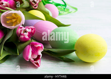 Easter arrangement with pink, green, yellow eggs  and tulips. Happy Easter greeting card or invitation. Stock Photo