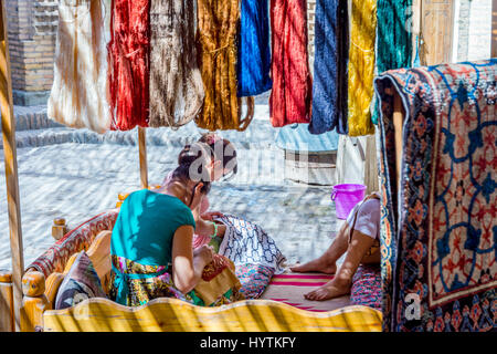 KHIVA, UZBEKISTAN - SEPTEMBER 7: Women embroidering the fabrics and clothes with traditional uzbek patterns. September 2016 Stock Photo
